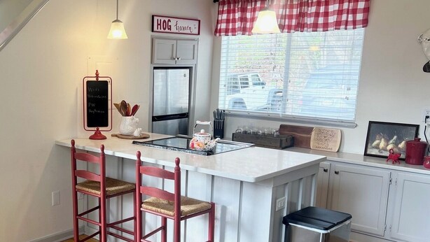 A kitchen with a central island, red chairs, a refrigerator, and a window with a view of the outside. - On Razorback Trail!  Walk to Dickson, Stadium & UARK (Fayetteville)