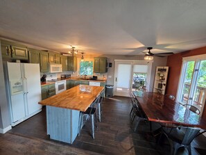 A kitchen with a central island, wooden countertops, green cabinets, and a dining area with a table and chairs. - Spacious 5-bedroom house in Sturgis. Centrally located in the heart of the hills (Sturgis)