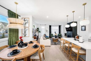 A modern living room with a sofa, coffee table, and dining area with a table set for two.