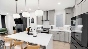 A modern kitchen with a central island, stainless steel appliances, and pendant lighting. - Downtown Raleigh Rooftop Retreat - Skyline Views (Raleigh)