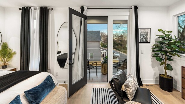 A modern bedroom with a bed, a sofa, a large window, and a balcony. - Downtown Raleigh Rooftop Retreat - Skyline Views (Raleigh)