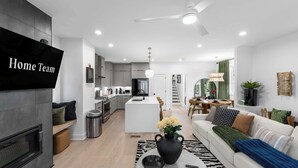 A modern living room with a sofa, coffee table, and a TV mounted on the wall. - Downtown Raleigh Rooftop Retreat - Skyline Views (Raleigh)