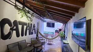 A cozy outdoor seating area with a hammock, a bar with a TV, and a large wall with the word "CATANA".
