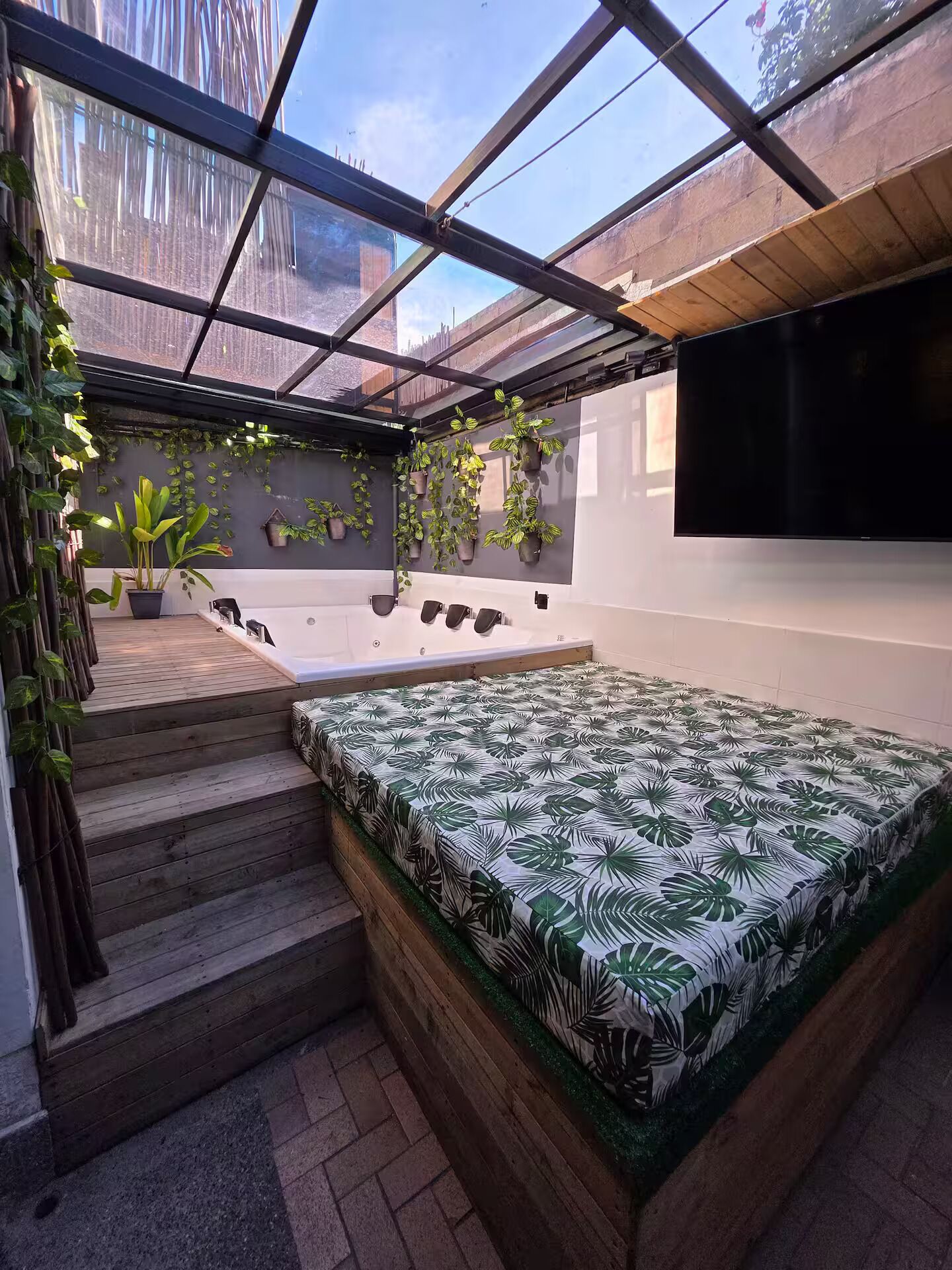 A sunroom with a bed, potted plants, and a TV.