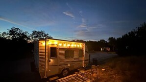 A motorhome with a covered porch area, a small seating arrangement, and a decorative rug. - StayNow @ The Mini Escape between New Braunfels & Canyon Lake (New Braunfels)