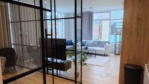 Sala de estar moderna com divisória de vidro, piso de madeira e vista para a cidade.