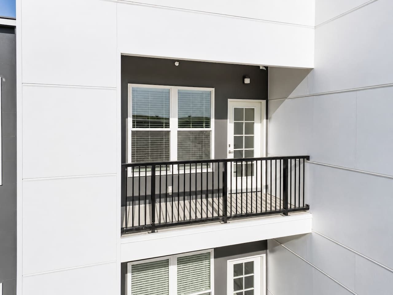 Un edificio de varios pisos con un balcón que tiene barandilla de metal negro.