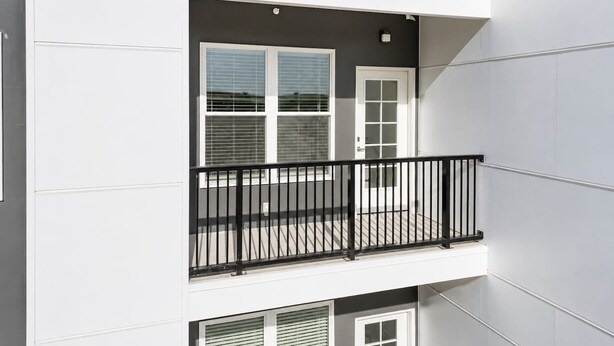 A multi-story building with a balcony featuring a black metal railing. - Stylish Suite • Downtown • Convention Center (Hot Springs)