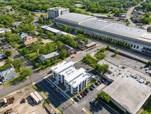 Ein Luftbild eines Gewerbegebiets mit einem großen Gebäude, Parkplätzen und umliegender Grünfläche.