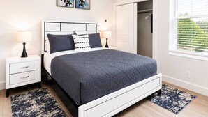 A bedroom with a bed, bedside tables, a wardrobe, and a window with blinds. - Stylish Suite • Downtown • Convention Center (Hot Springs)