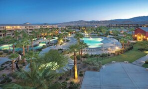 Ein Resort mit mehreren Schwimmbecken, Palmen und einer Bergkulisse.