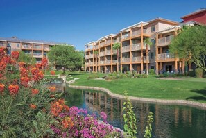 Ein mehrstöckiges Hotel mit Balkonen, einem Innenhof und einem kleinen Teich.