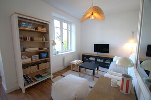 Un salon confortable avec une bibliothèque, un téléviseur, une table et une fenêtre.