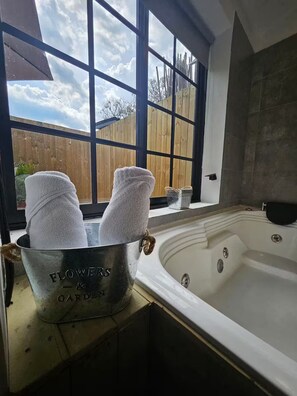 A bathroom with a large window, a bathtub, and a bucket labeled "FLOWERS & GARDEN" containing towels. - Party AGUA House Medellin 5BR w/5Hot tub (Medellín)