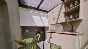 A compact kitchen with a wooden countertop, a sink, and a shelf with wine glasses. - Party AGUA House Medellin 5BR w/5Hot tub (Medellín)