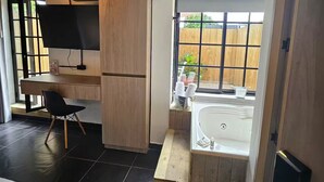 Une cuisine moderne avec un plan de travail en bois, un réfrigérateur encastré et une fenêtre donnant sur une clôture en bois.