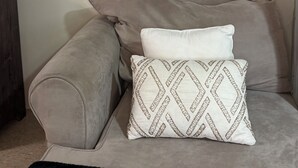 A sofa with two pillows, one plain and one with a geometric pattern. - Private Suite: Hotel Perks, Snacks & Fast WiFi near Baltimore & Top Hospitals (Nottingham City)