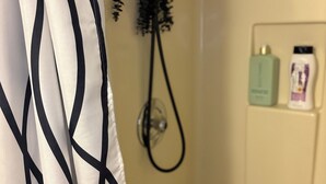 A bathroom with a shower, a towel rack with a hairdryer, and toiletries on the wall. - Private Suite: Hotel Perks, Snacks & Fast WiFi near Baltimore & Top Hospitals (Nottingham City)