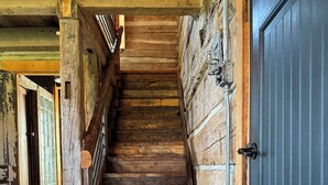 Un escalier en bois, avec une porte bleue en haut, mène à une pièce dotée d’un plancher en bois et d’un tapis.