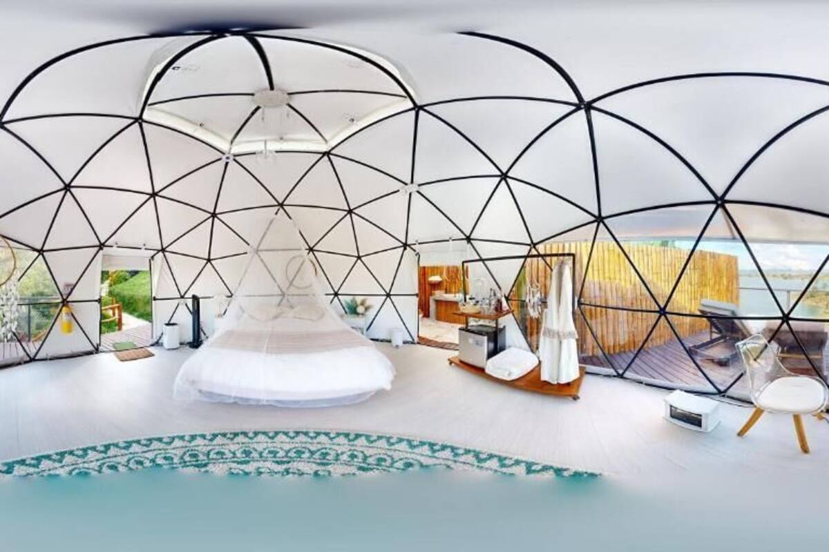 Un interior moderno con diseño geométrico, una lámpara colgante central, piso con diseño y vistas al exterior.