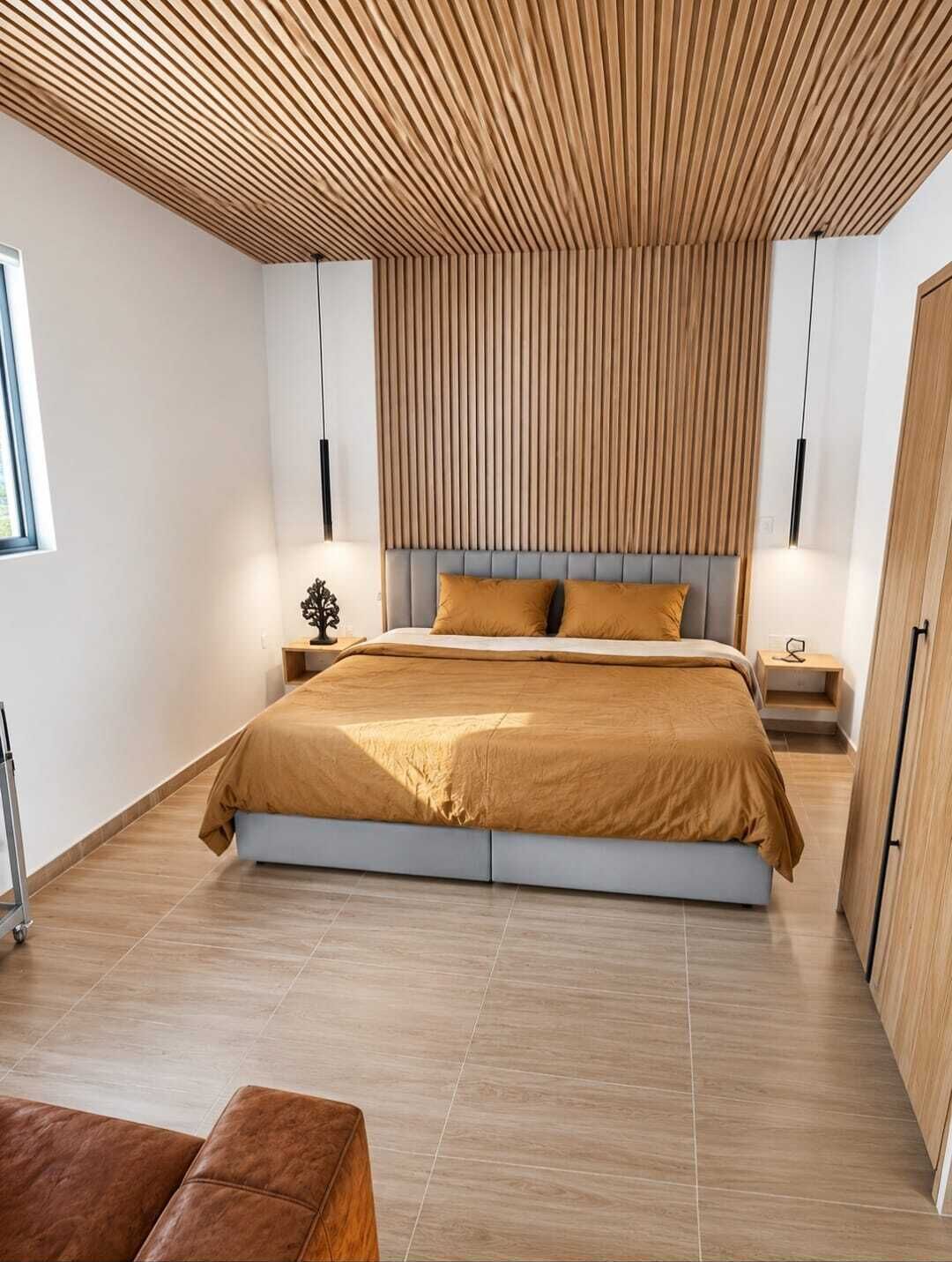 Un dormitorio moderno con una cama grande, techo de listones de madera y diseño minimalista.