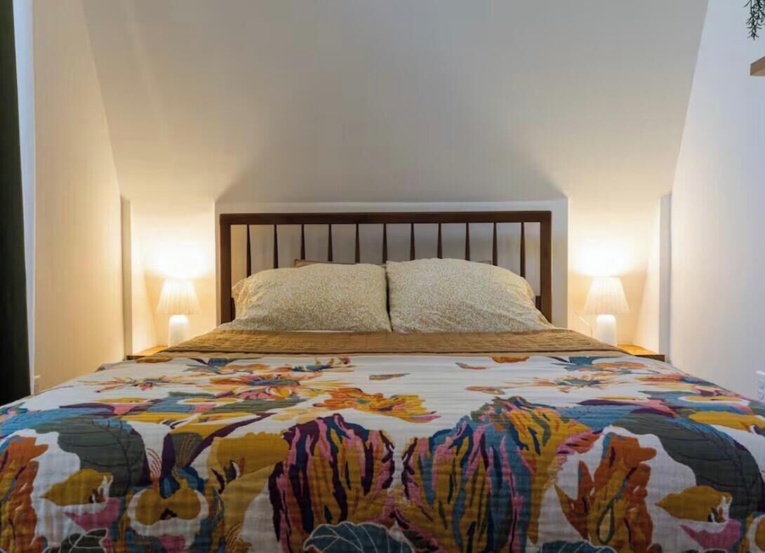 Un dormitorio con una cama, dos lámparas de noche y una colcha estampada con motivos florales.