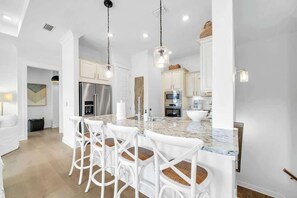 A modern kitchen with white cabinetry, a granite countertop, and a stainless steel refrigerator. - Summer Wind 30A by Stay on 30a (Inlet Beach)