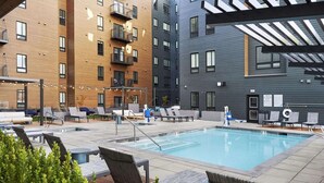 A rooftop pool area with lounge chairs, a swimming pool, and multi-story buildings in the background. - Top Floor, Lounge, King Bed, BSU (Boise)