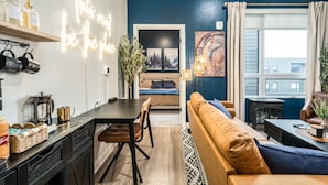 A modern living room with a sofa, coffee table, and a dining area with a table and chairs. - Top Floor, Lounge, King Bed, BSU (Boise)