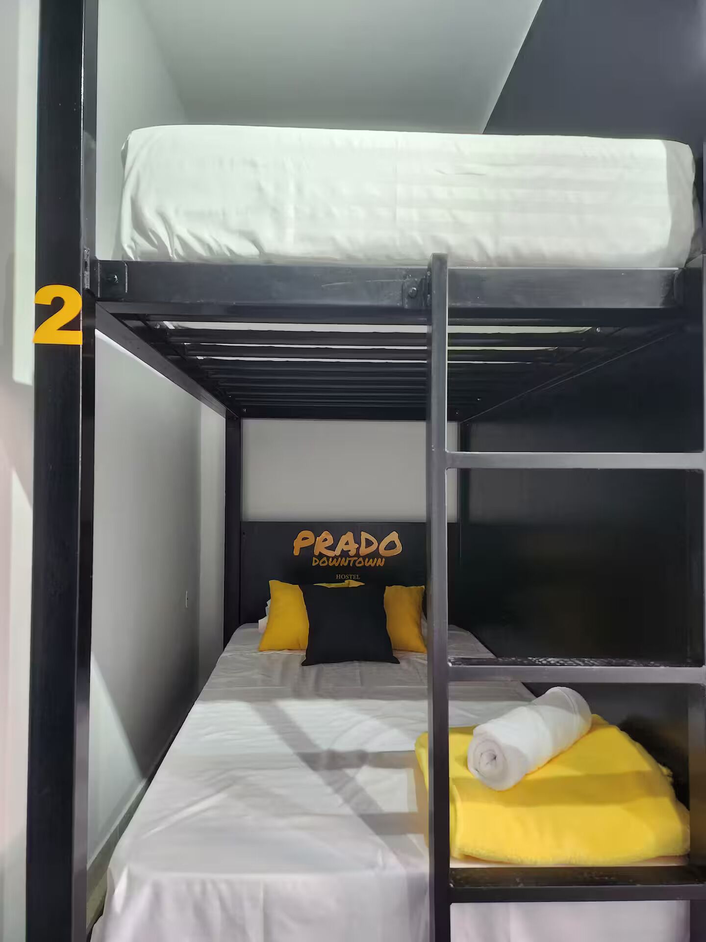 Een stapelbed met een hoofdeinde waarop "Prado Downtown Hostel" staat.