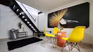 A modern living room with a staircase, a large abstract painting, and bright yellow chairs. - Prado House in Medellin 8BR & Terrace (Medellín)