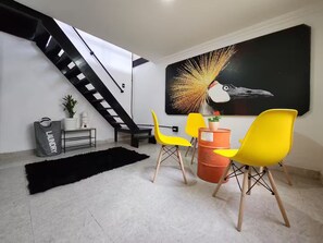 Ein modernes Wohnzimmer mit Treppe, einem großen abstrakten Gemälde und leuchtend gelben Stühlen.