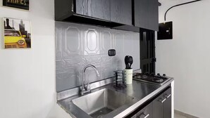 A modern kitchen with a stainless steel sink, black cabinets, and a white backsplash. - Prado House in Medellin 8BR & Terrace (Medellín)