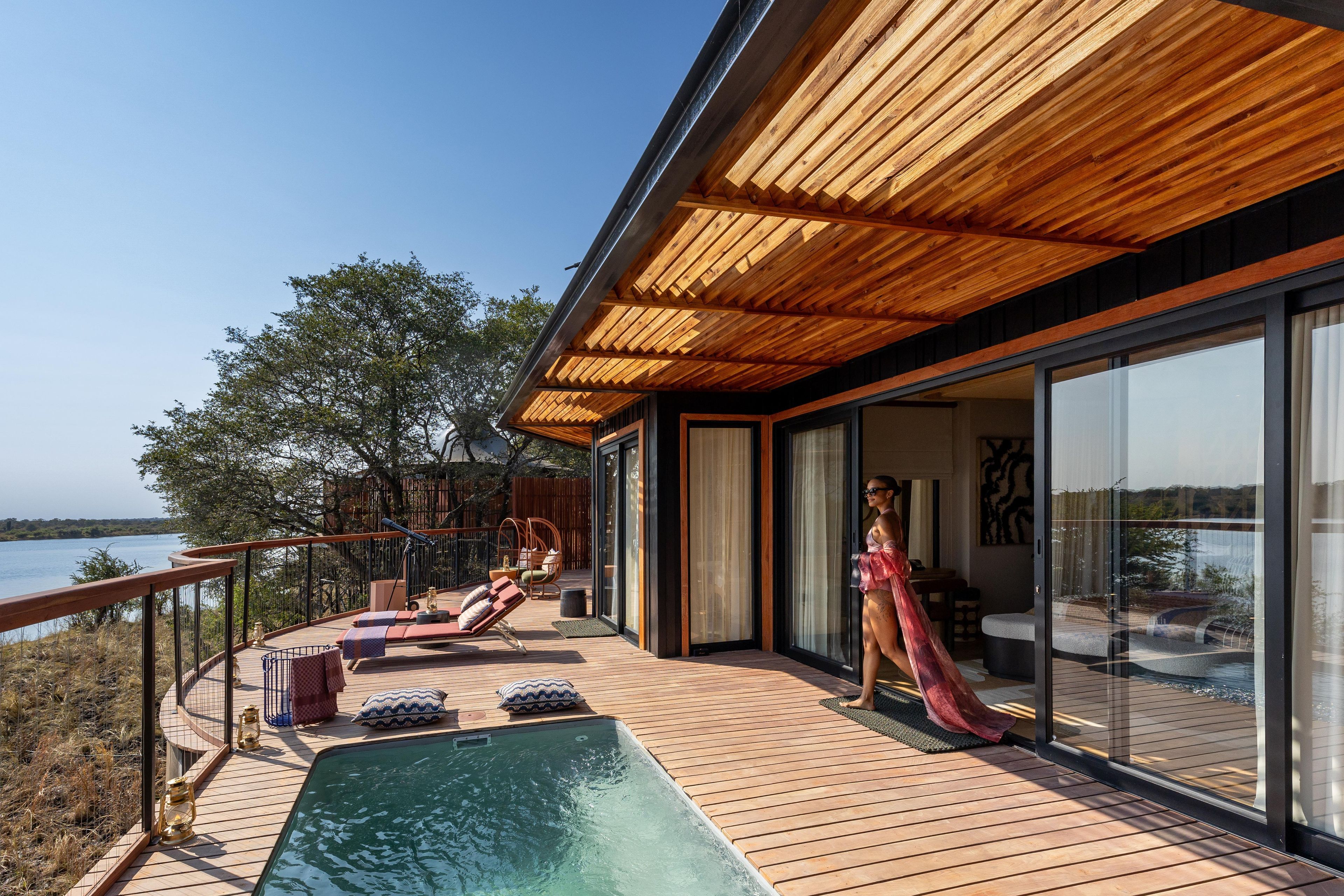A modern outdoor deck with a pool, lounge chairs, and a view of the water.