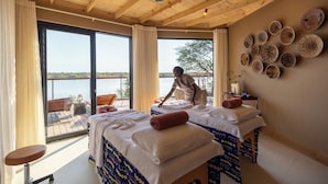 Ein Zimmer mit zwei Betten, einem Deckenventilator, großen Fenstern und Blick auf das Wasser.