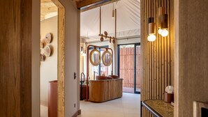 A corridor leading to a room with a wooden bar and a large mirror. - Anantara Tented Camp Kafue River (Kafue National Park)