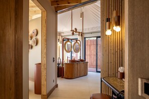 A corridor leading to a room with a wooden bar and a large mirror. - Anantara Tented Camp Kafue River (Kafue National Park)