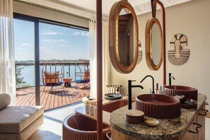 A modern bathroom with a large window, a wooden vanity with two sinks, and a mirror with an ornate frame. - Anantara Tented Camp Kafue River (Kafue National Park)