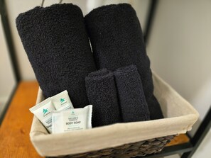 A basket containing three black towels and two tubes of body soap.