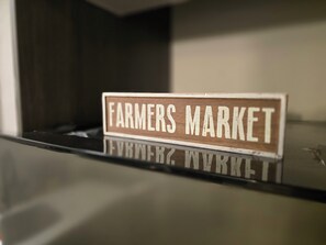 A wooden sign with the text "Farmers Market" on a reflective surface.