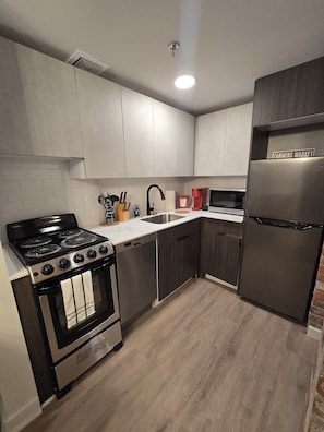A modern kitchen with a black stove, stainless steel dishwasher, and a refrigerator labeled 'Farmers Market'. - Downtown Detroit Wlk - LittleC Arena Ford Field, Comerica Park, DMC, Wayne State (Detroit)