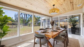 A dining area with a wooden table, chairs, and a hanging light fixture. - Casa del Sol - Venice Island Beach Escape (Venice)