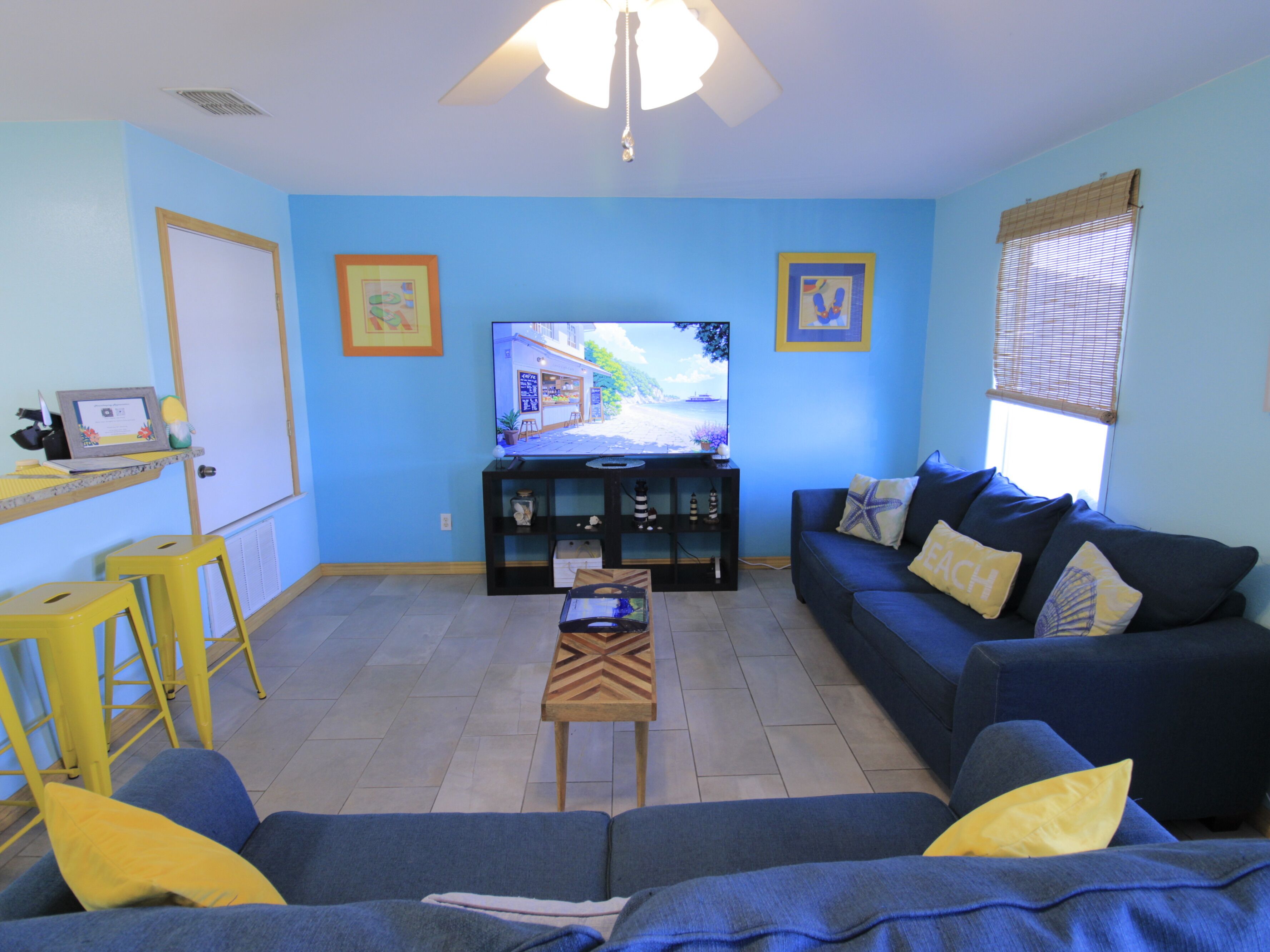 A living room with a sofa, a coffee table, a TV, and a small table with a laptop.