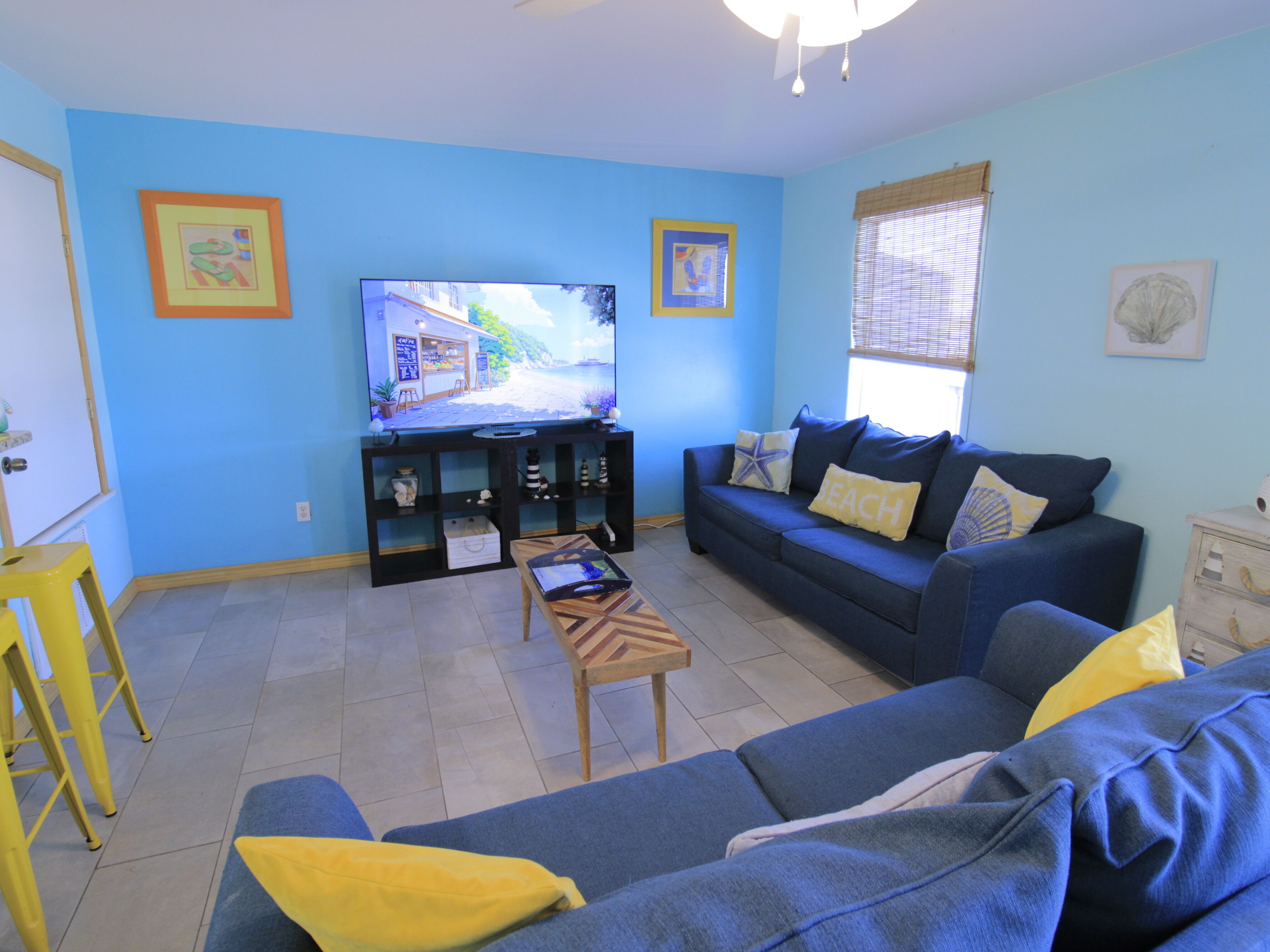 Una sala de estar con un sofá azul, un televisor y una mesita.