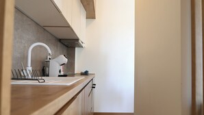 A modern kitchen with wooden cabinets, a white countertop, a sink, and a range hood. - Valmere Apartment Tivat Sea View Free Parking (Tivat)
