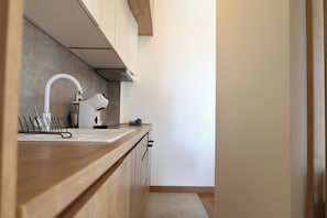 Eine moderne Küche mit Holzausstattung, einer weißen Arbeitsplatte, einer Spüle und einer Dunstabzugshaube.