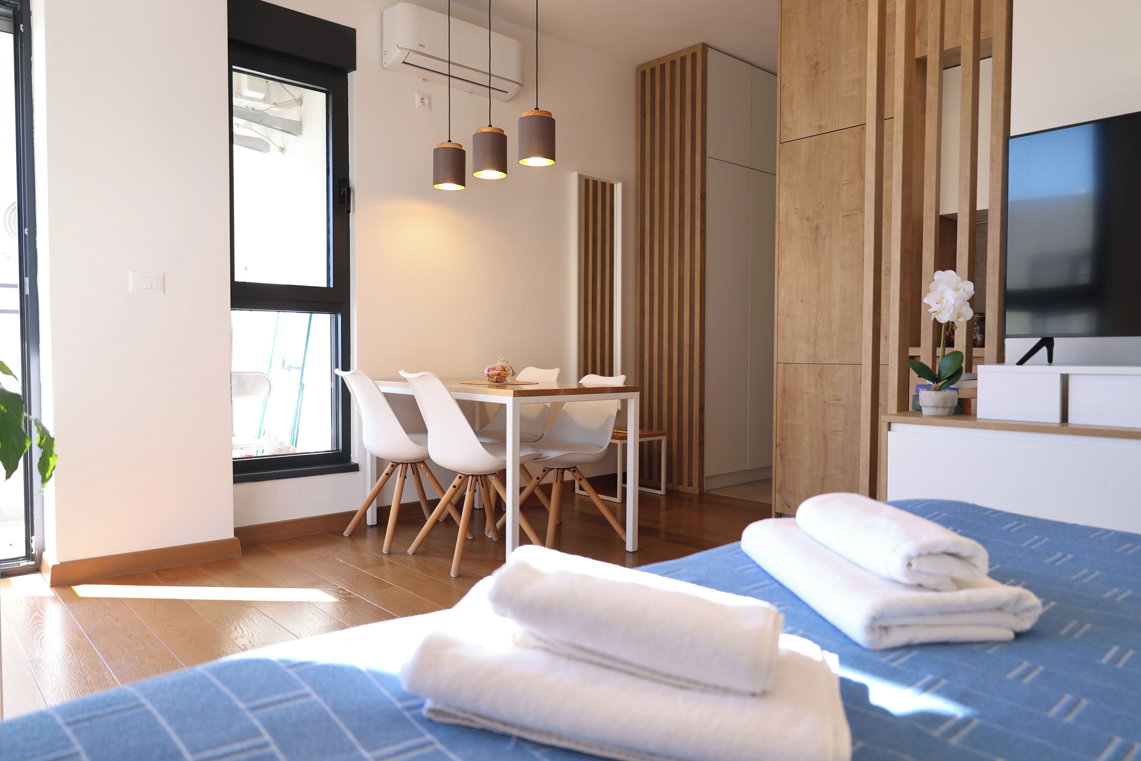 Ein modernes Hotelzimmer mit Bett, Schreibtisch mit Stühlen, Fernseher und Fenster.