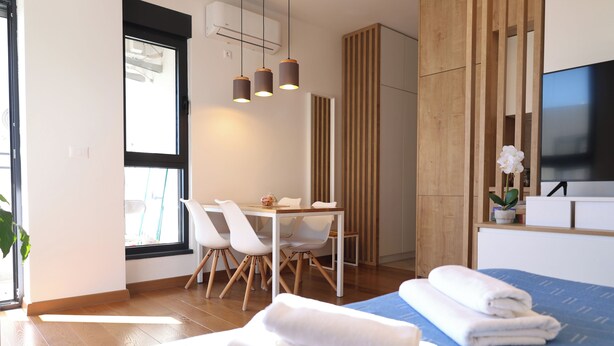 A modern hotel room with a bed, a desk with chairs, a TV, and a window. - Valmere Apartment Tivat Sea View Free Parking (Tivat)