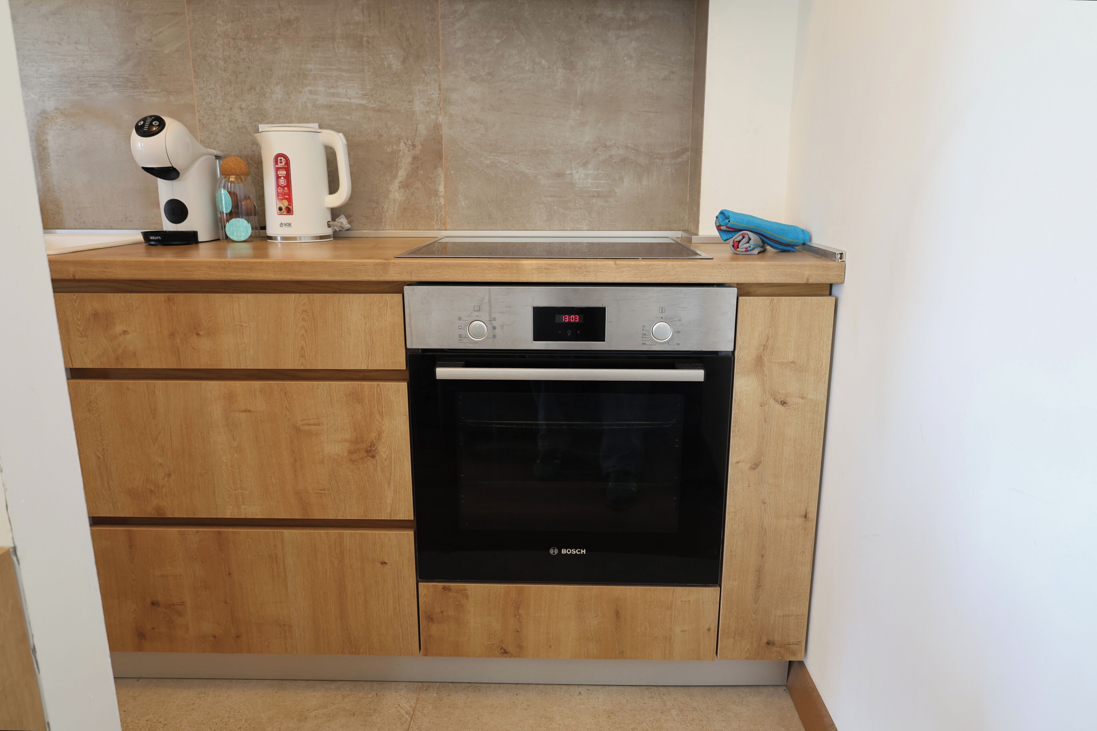 Una cocina con horno Bosch, cafetera y hervidor sobre la encimera.