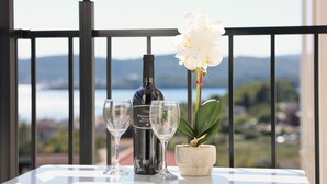 A balcony with a table, a bottle of wine, two glasses, and a potted orchid. - Valmere Apartment Tivat Sea View Free Parking (Tivat)